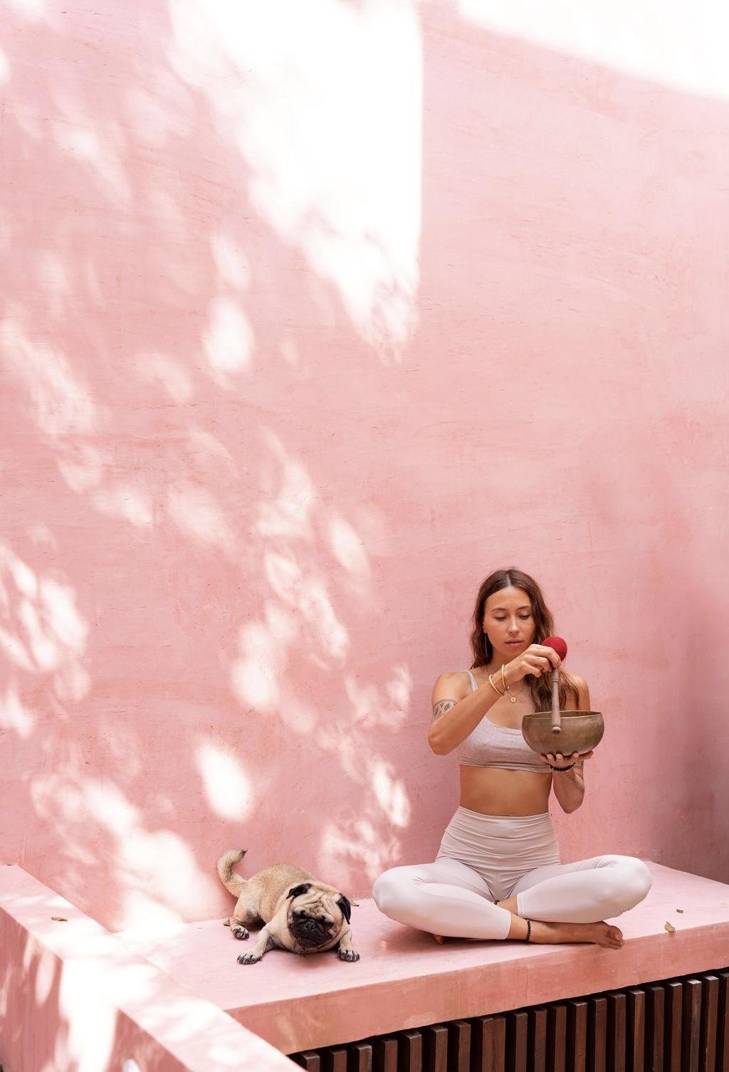 Natalia Orlova sitting with a singing bowl, her dog beside her